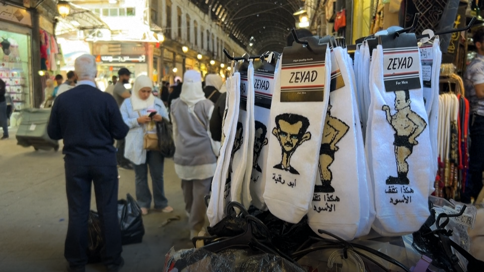 Suriye, Şam, Beşar Esad, çorap, karikatür, hiciv, mizah, ticaret, rejim, protesto, Ziad Zaouit, Bassel al-Sati, Maher el-Assad, Captagon, Erdoğan, siyaset, devrim, baskı, ifade özgürlüğü, ironi, Suriye ekonomisi, Şam ticareti
